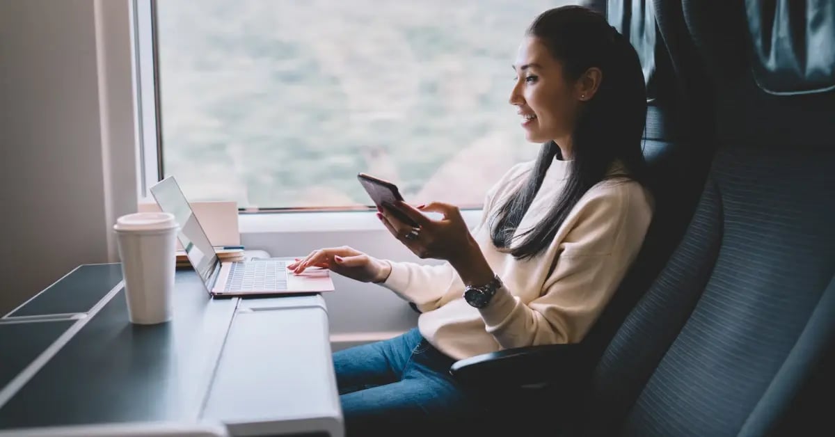 Businesswoman traveling on a train on her phone and laptop