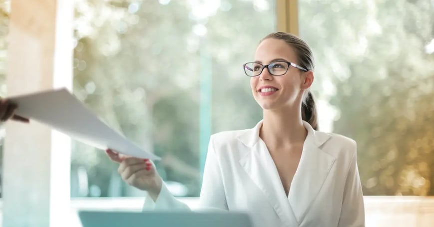 Executive Assistant handing off a offsite locaiton plan to her boss