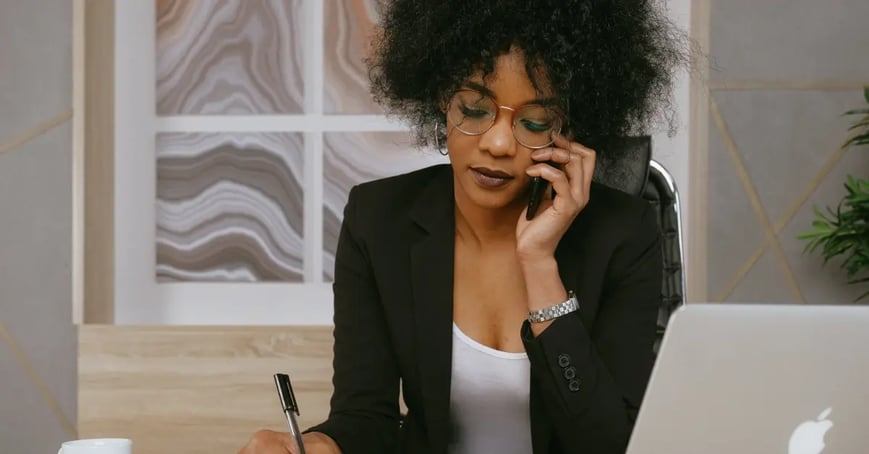 Executive Assistant on the phone as she writes notes down about the upcoming offsite