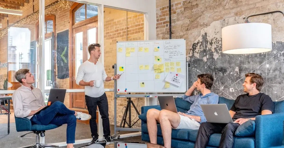 A team sitting in an office with an Executive Assistant talking about budgeting in front of a white board
